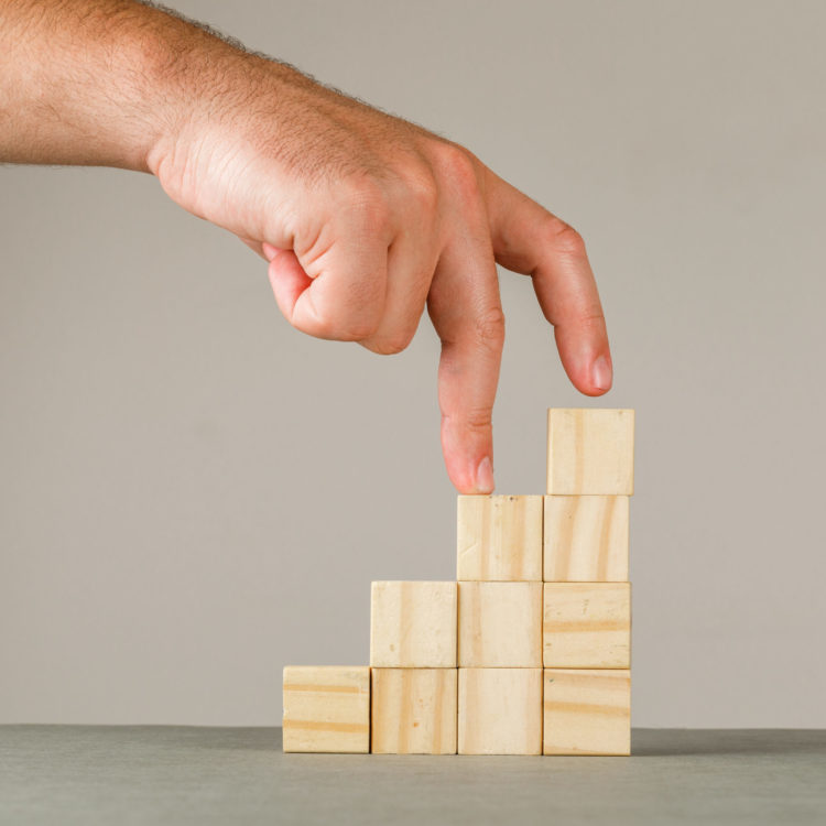 concept-croissance-entreprise-vue-laterale-du-mur-gris-blanc-homme-mettant-doigts-dans-escaliers